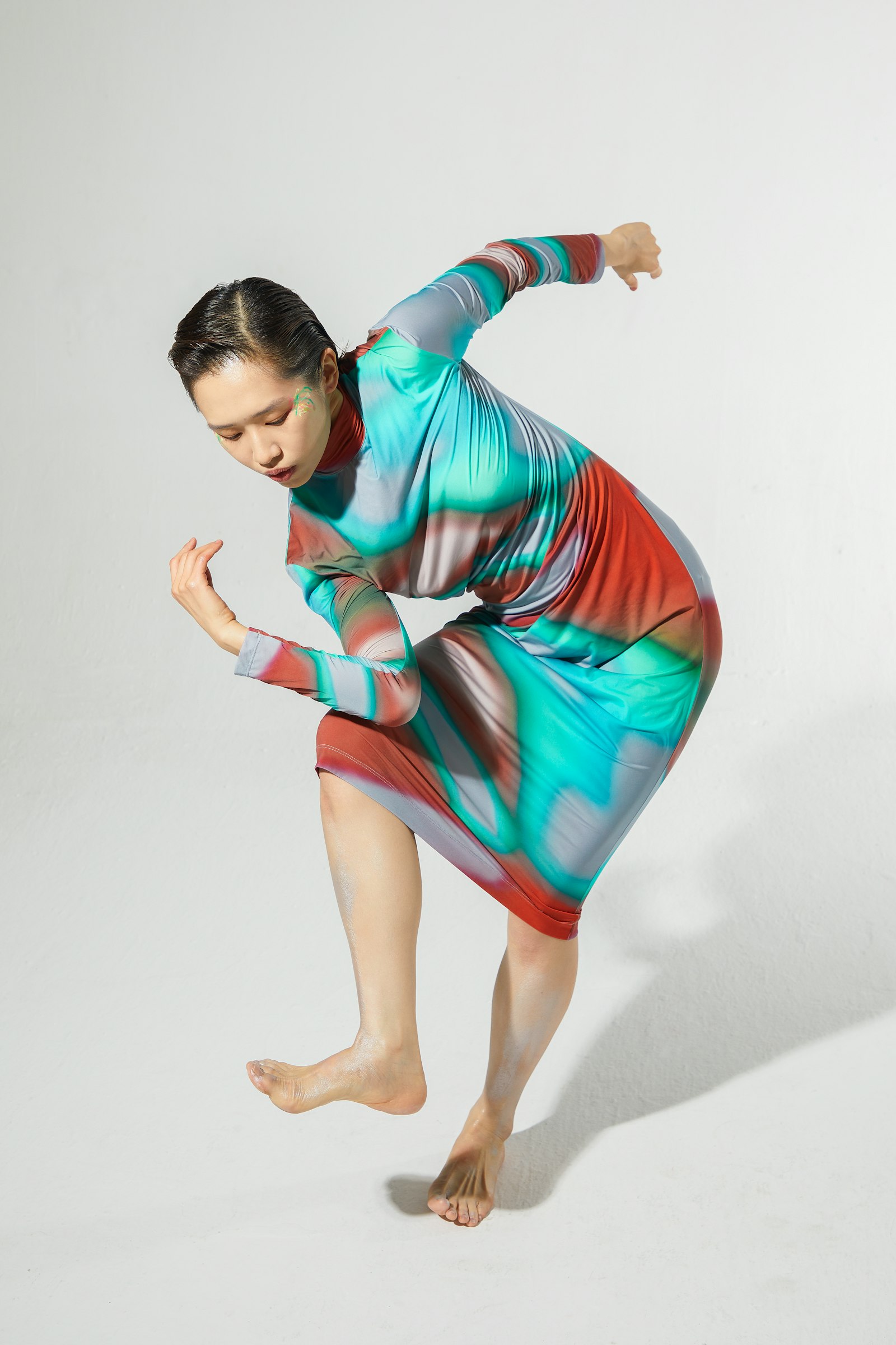 A dancer mid-movement against a plain studio backdrop
